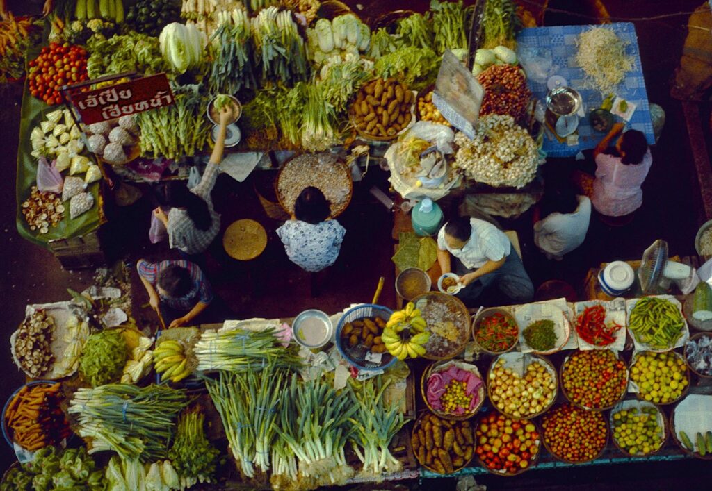 overhead shot of market vegetable sellers with variety of vegetables.