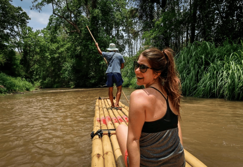 a tourist sitting on a bamboo raft rafting along the Mae Wang river with many green trees along the river